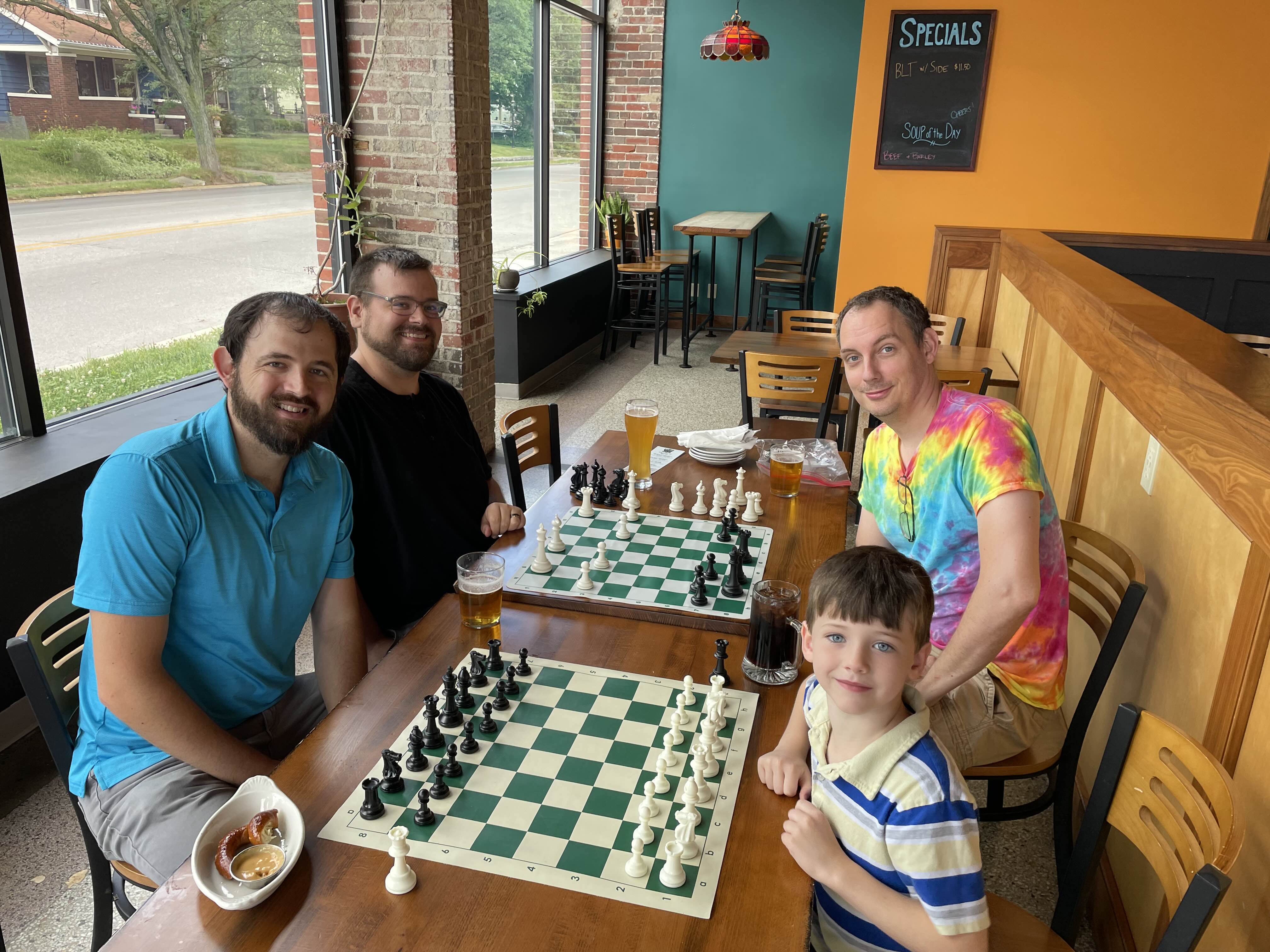 Club members of different ages smiling around two chessboards